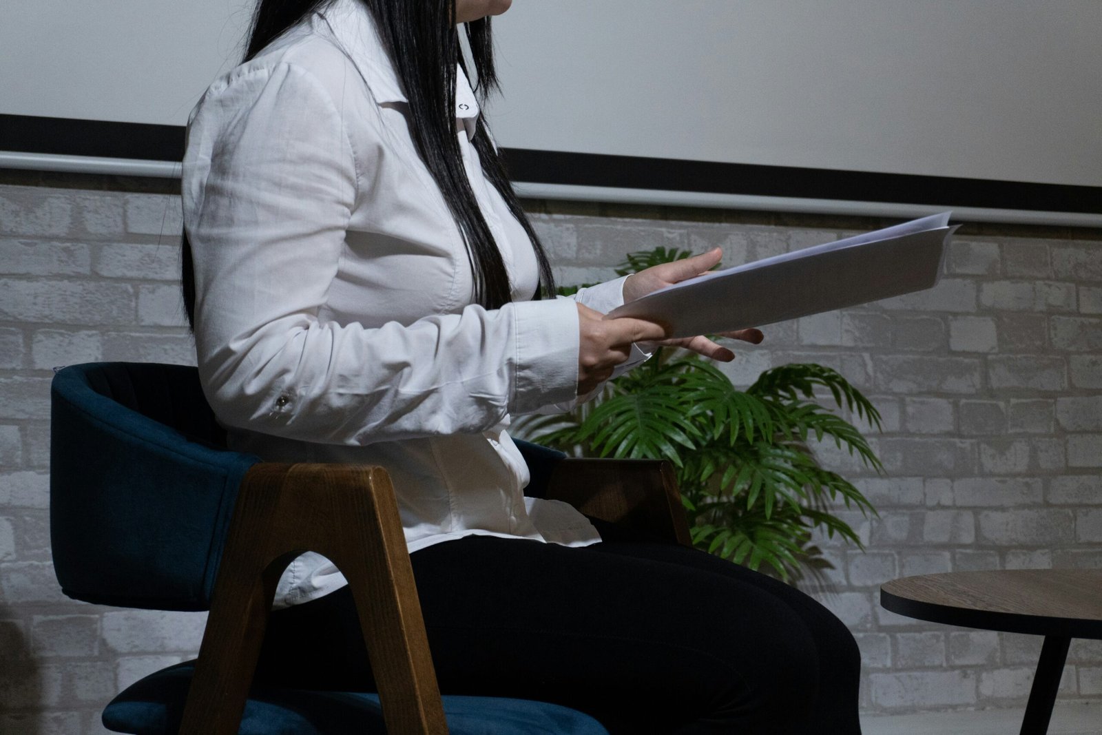 A woman holds a tablet and sits in a chair.
