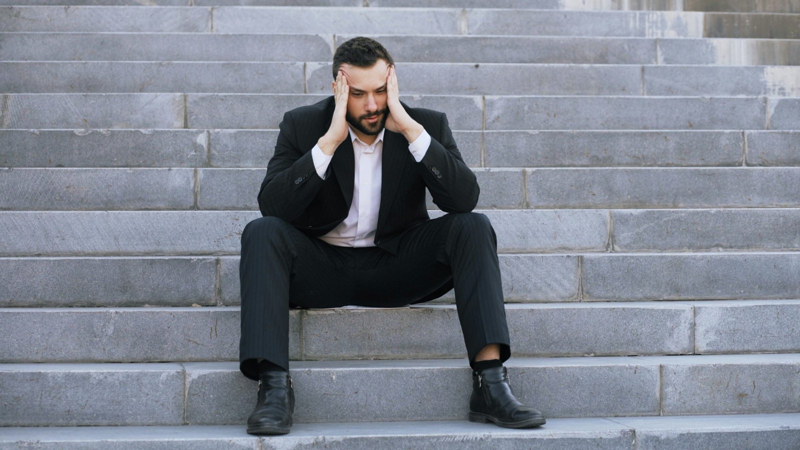 Man in suit sitting on stairs with head in hands