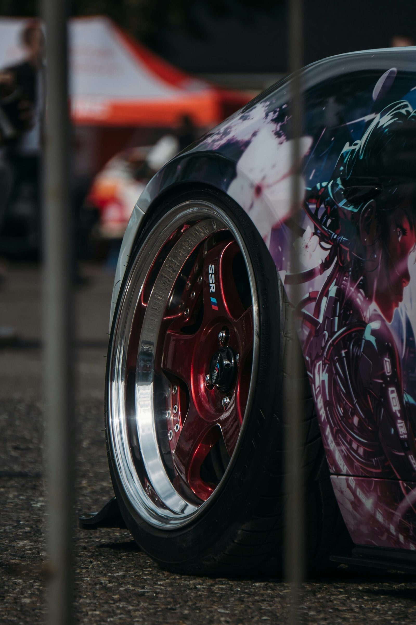 Customized car with anime art and red rims.
