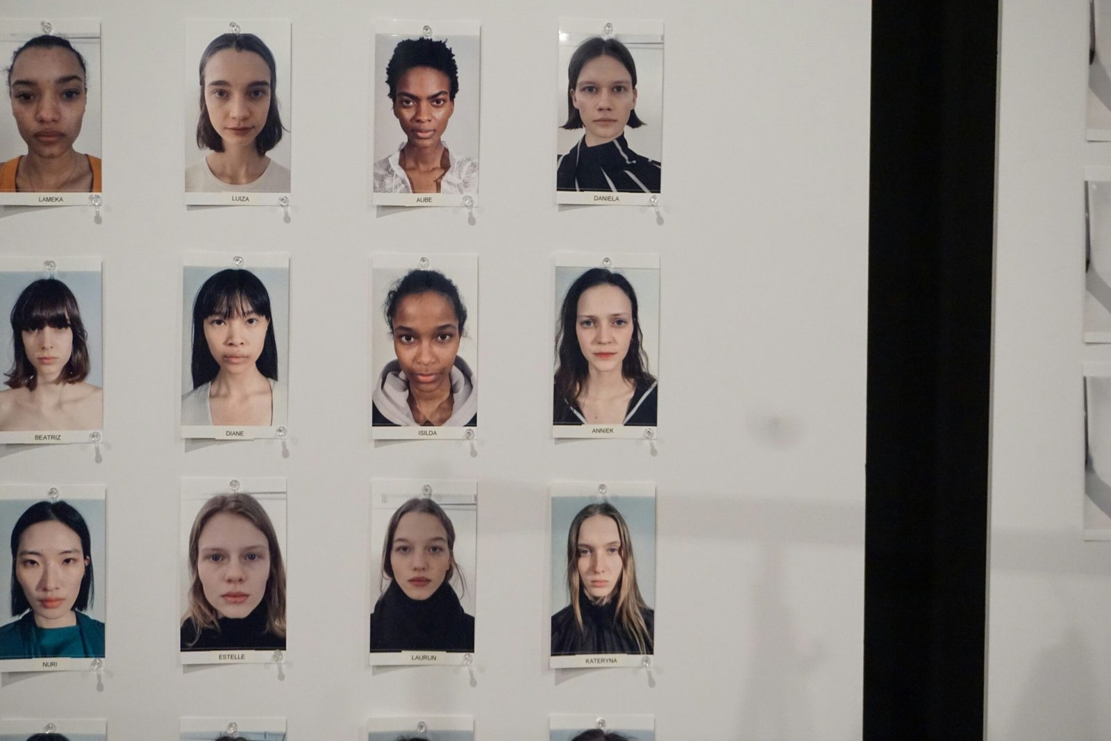 Grid of diverse young women's headshots on wall