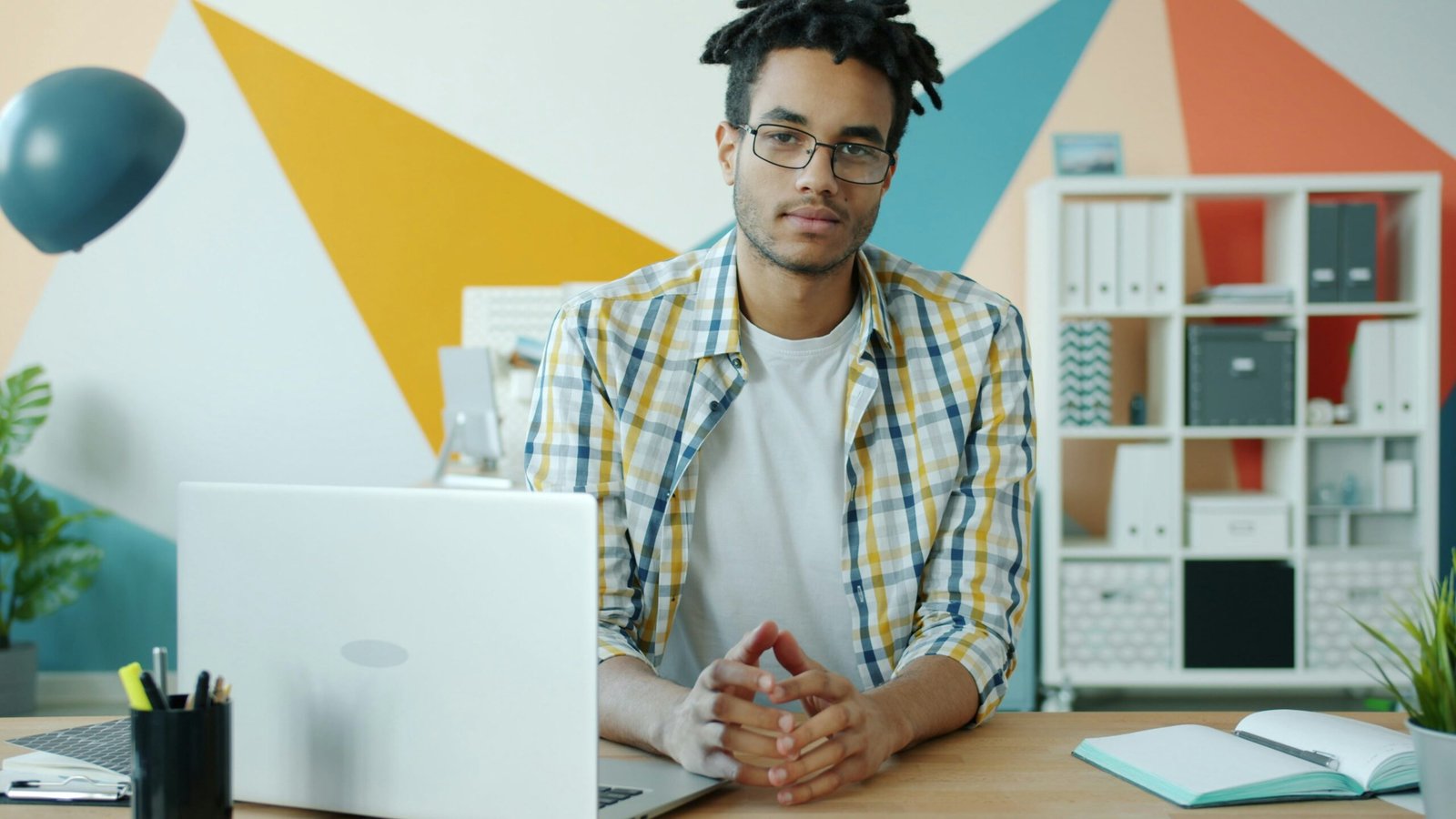 Man with dreadlocks sitting at desk with laptop.