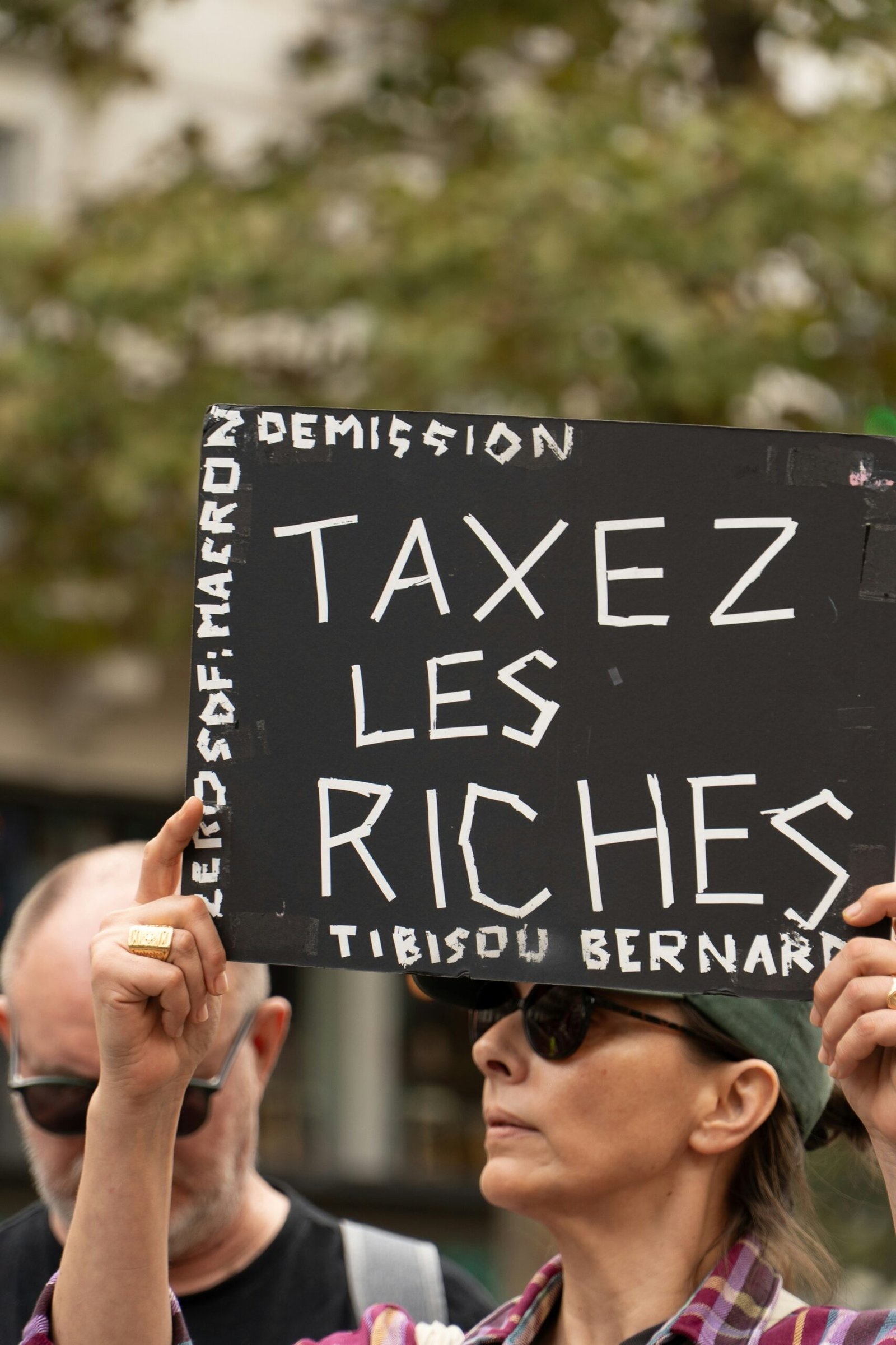 Protesters hold sign demanding to tax the rich.